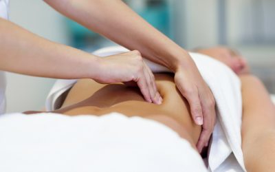 Female patient is receiving treatment by professional osteopathy therapist. Woman having abdomen massage in a physiotherapy center.